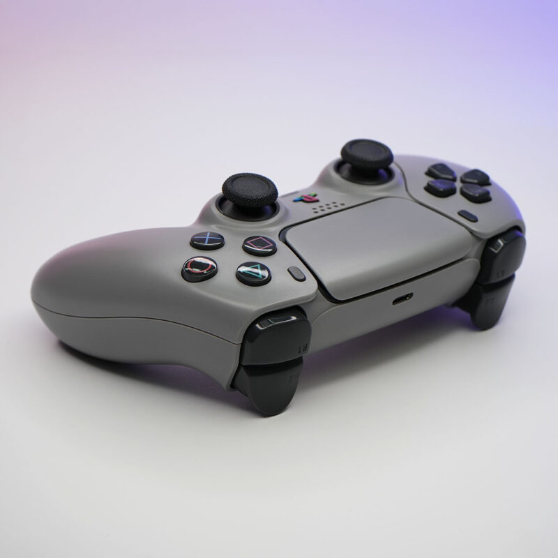 Angled view of 1080R PlayStation Retro Grey 30th Anniversary PS5 Controller with DualSense style buttons and D-Pad
